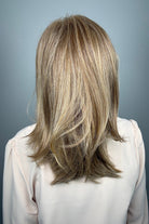 Woman wearing layered golden blonde wig with bangs (Whisper by Henry Margu in 12/26H)
