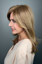 Woman wearing layered golden blonde wig with bangs (Whisper by Henry Margu in 12/26H)
