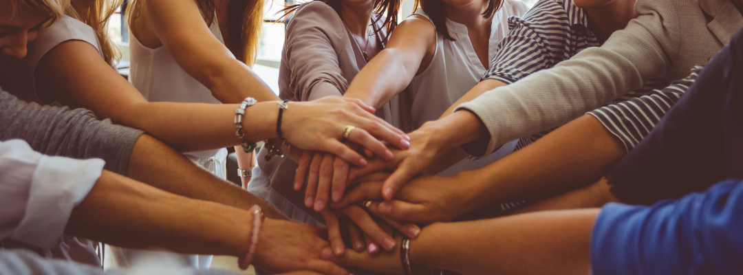 Group of people putting their hands together in a circle.