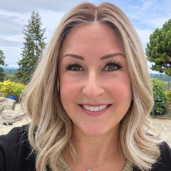 Andrea wearing Keeley heat friendly synthetic wig in champagne blonde rooted outdoors with a tan top and black sweater.