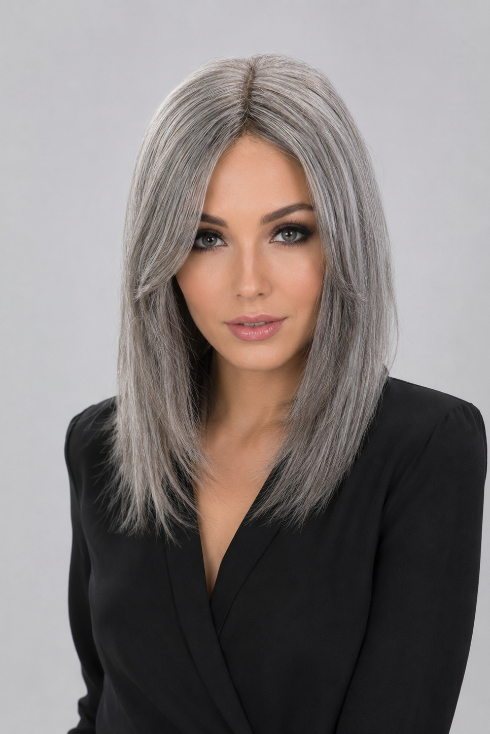 Woman wearing a Bespoke human hair wig by PUSH hair in color Sage, wearing a black blouse against a light grey background - front view