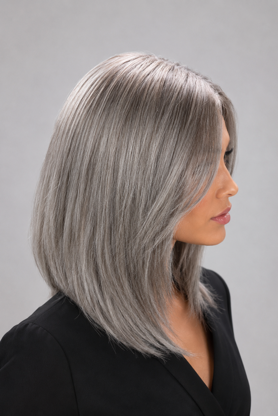 Woman wearing a Bespoke human hair wig by PUSH hair in color Sage, wearing a black blouse against a light grey background - right side view