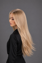 Woman wearing Bespoke Human Hair Wig by PUSH 20-26" in color Soleil with black blouse and black pants. Left side view.