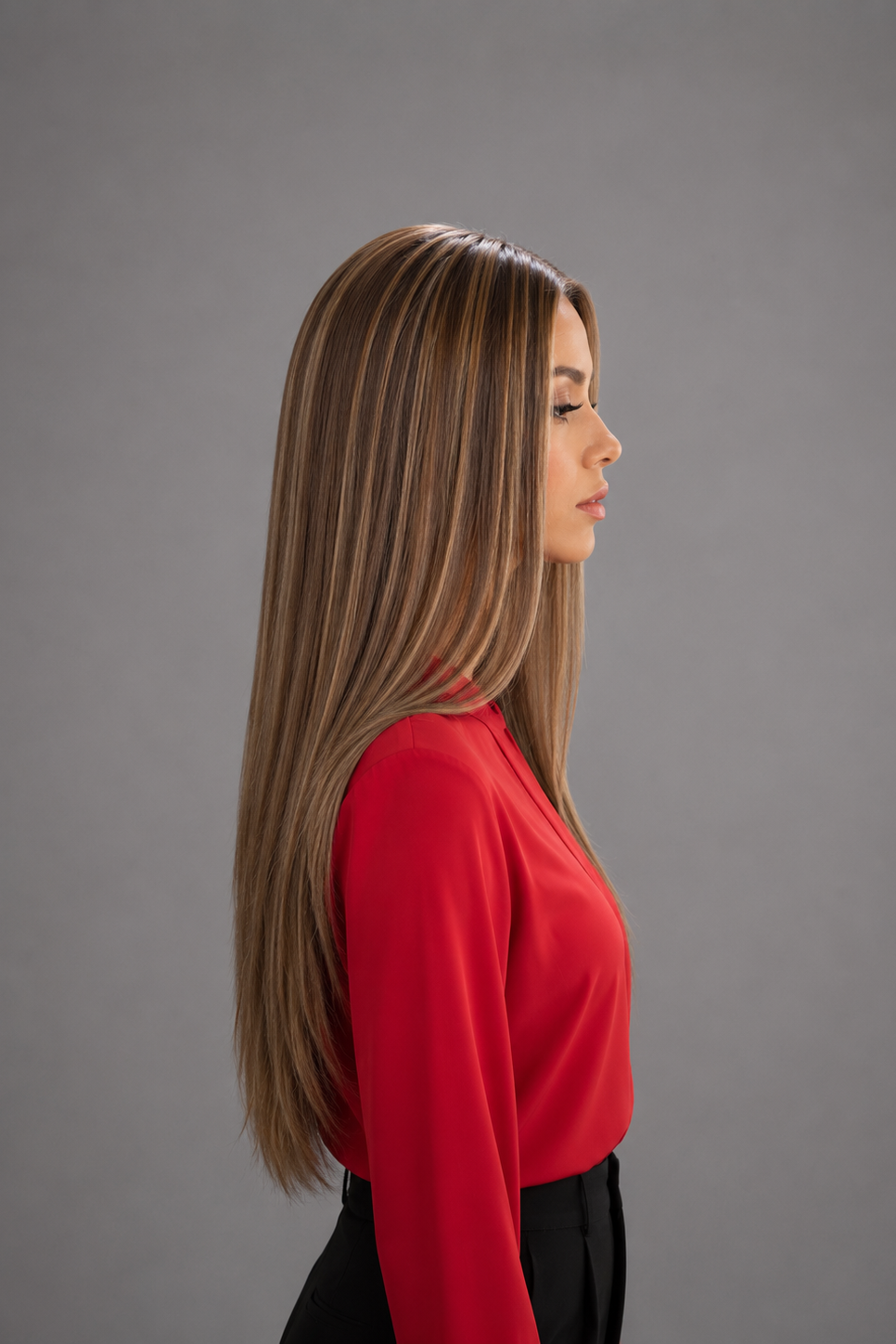 Woman wearing a Bespoke Human Hair Wig by PUSH in color Jolie and a red colored button down blouse with black pants. Right side view.