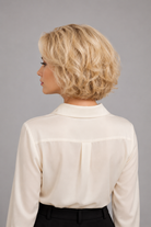 Woman wearing Bespoke Human Hair Wig 5-13" in color Blond Platine Racine Miel with cream colored button down blouse. Back view.