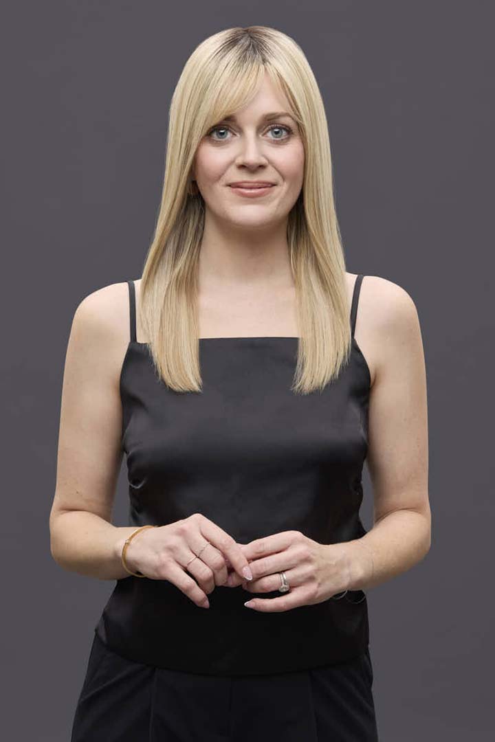 Woman wearing a 14-inch blonde Remy human hair topper with a natural monofilament base and soft bangs.