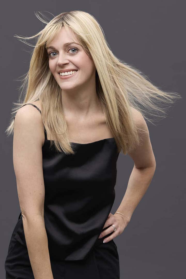 Woman wearing a 14-inch blonde Remy human hair topper with a natural, lightweight monofilament base.