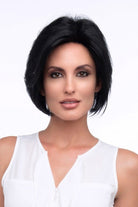 A woman wearing Abbey by Envy - A Human Hair and Heat Friendly Synthetic Blend wig in color black with a white sleeveless top against a white background.