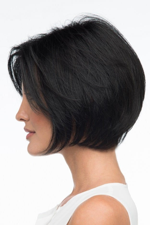 A woman wearing Abbey by Envy - A Human Hair and Heat Friendly Synthetic Blend wig in color black with a white sleeveless top against a white background. Side view. 